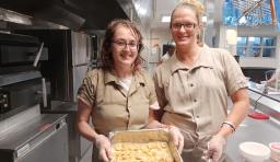 Two women enrolled in a jail education culinary program show the dessert that they made. 