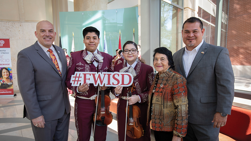 Jacinto Ramos and a group of people including students hold a "#FWISD" sign and smile for the camera