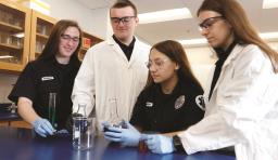 Students in lab coats work with beakers