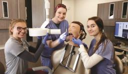 Dental students smile at the camera with a medical mannequin 