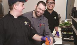 Culinary students laugh and smile while preparing food