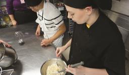Culinary students mix food in a bowl