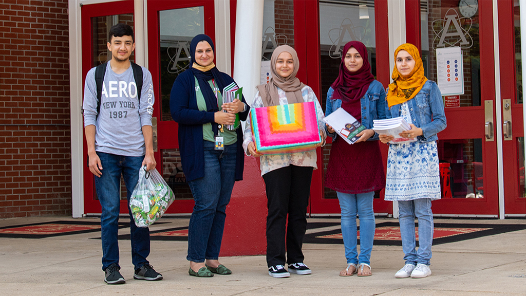 students and an assistant principal hold supplies for refugees