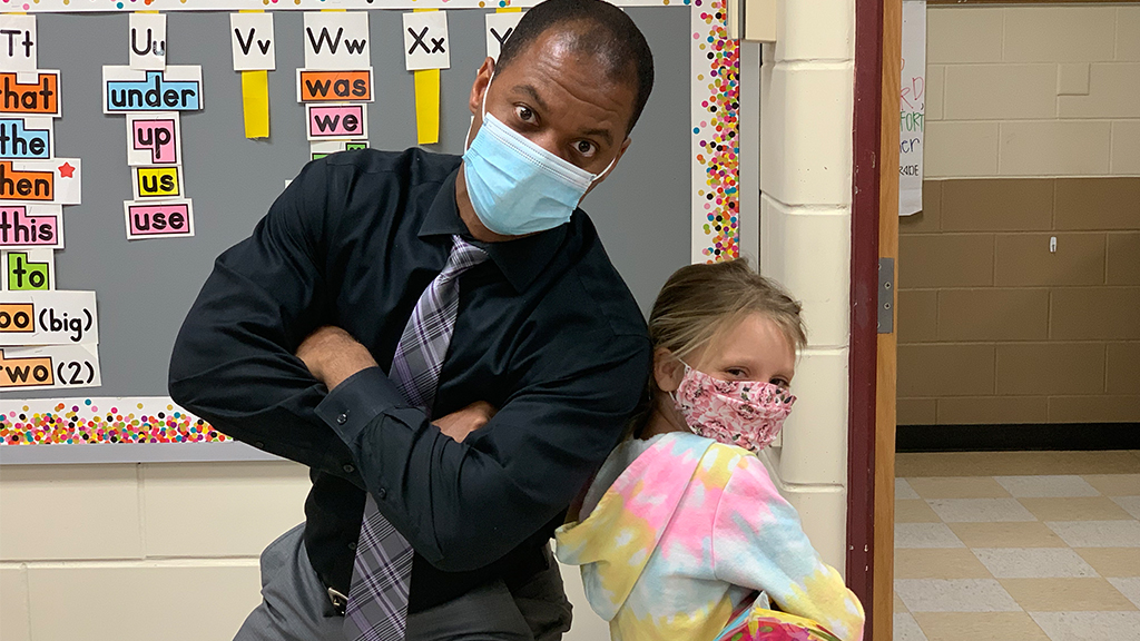 a faculty/staff school member and a student pose for the camera while wearing masks