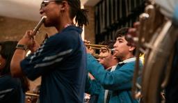 students play in band, a flutist and trumpet player are visible 