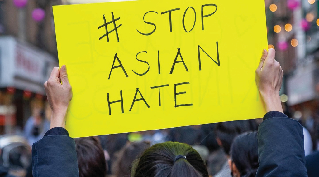 A girl holds up a sign that reads  #Stop Asian Hate