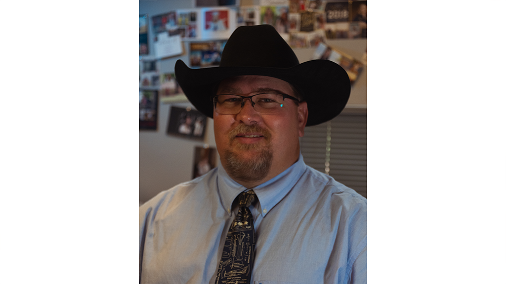 A man in a shirt and tie also wears a cowboy hat.
