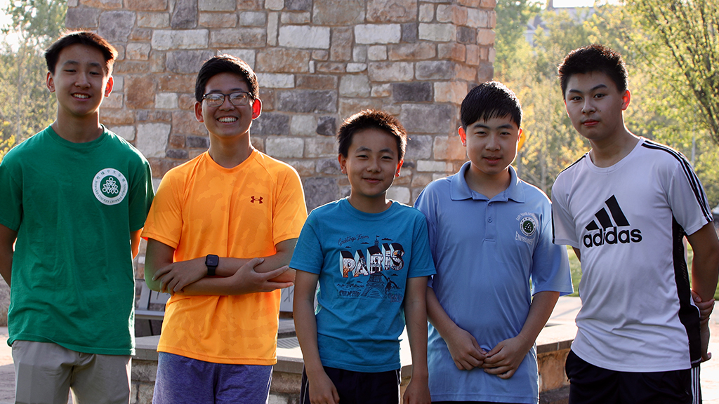 Five Asian American male students smile at the camera.