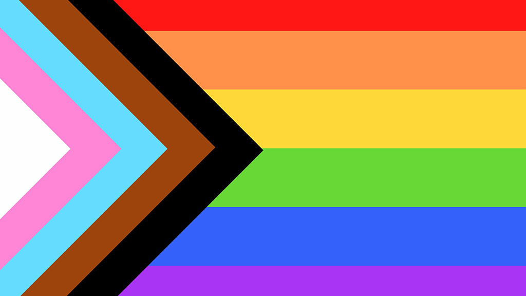 Photo of the Progress Pride Flag which features the colors black, brown, turquoise, pink, and white in an arrow shape to the traditional stripped rainbow flag to better represent the diversity of the LGBTQ community.