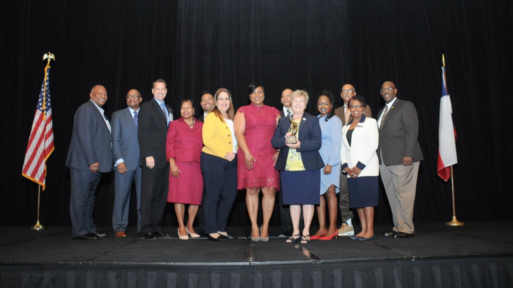 The school district stands on stage holding their award