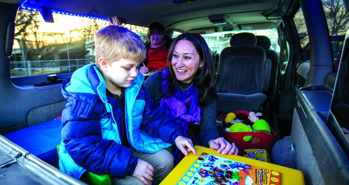 A child and adult playing an educational game inside a van